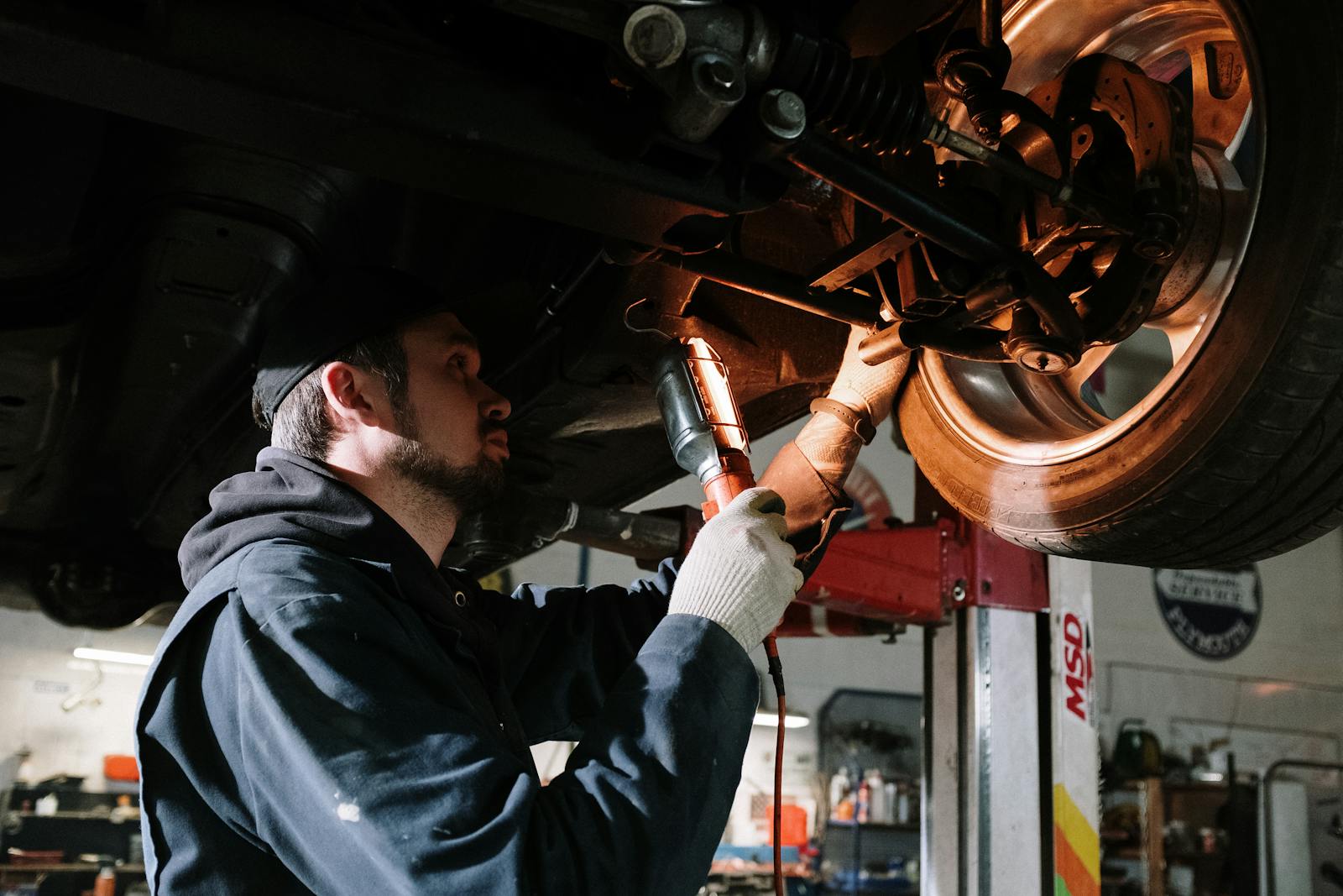 Mechaniker prüft das Fahrwerk eines auf der Hebebühne befindlichen Autos in der Werkstatt